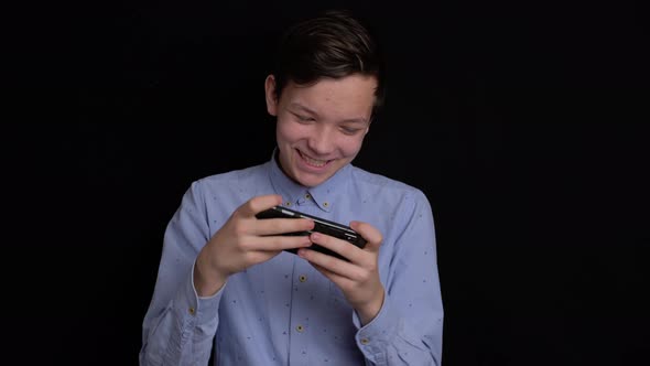 Teen Smiling and Using Mobile Phone on Black Background.