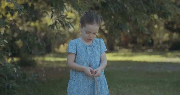 Cute little girl wearing a blue dress playing alone outdoors