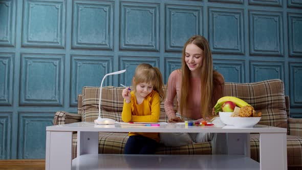 Lovely Mother Babysitter Teacher Helping Kid Daughter with Homework Learning Writing at Home