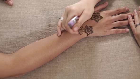 Woman Is Doing Body Art By Henna on Hands of Girl, Close-up From Top