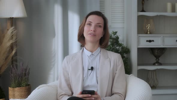 Young beautiful girl, blogger, vlogger, influencer, sitting at home, talking, looking at the camera