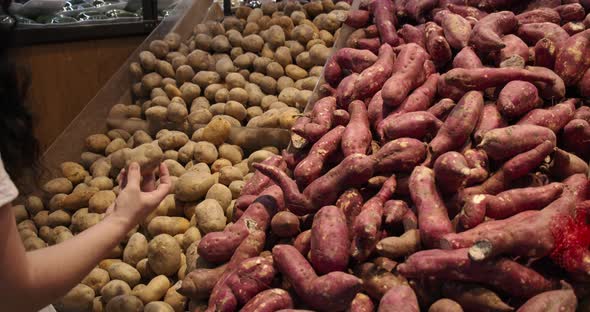 Young Woman in the Grocery Section of a Supermarket Picks Up a Bag of Potatoes to Be Weighed on a