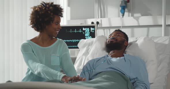 African Wife Visiting Ill Husband in Hospital Room