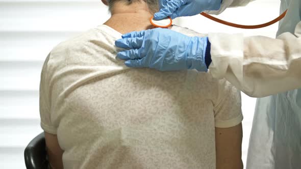 Female Doctor Listens with a Phonendoscope to an Elderly Patient with Symptoms of Coronavirus