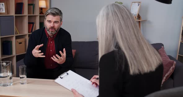 Crop View of Mature Man Sitting on Couch and Having Therapy Session with Female Person
