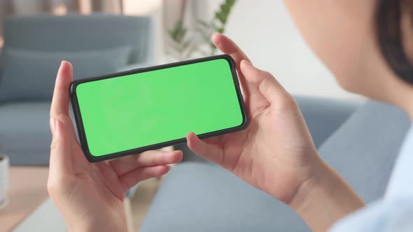Hands Female Holding Smartphone With Green Screen In Living Room