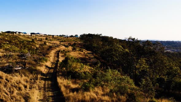 A drone follows a dirt road over a beautiful grassland