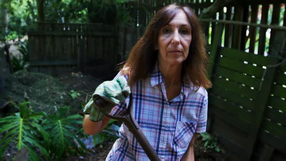 Mature woman using gardening fork in the garden