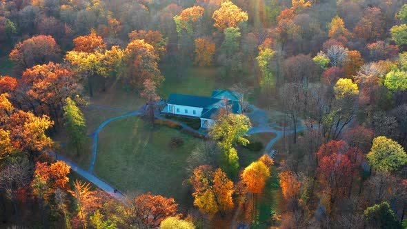 Flight in the evening over trees, park, building. The trees are covered with red, yellow.