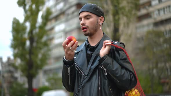 Positive Young LGBTQ Man Smelling Delicious Vitamin Apple Looking at Camera Smiling