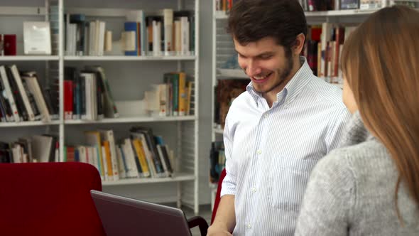 Male Student Shows His Female Classmate Something on Laptop at the Library