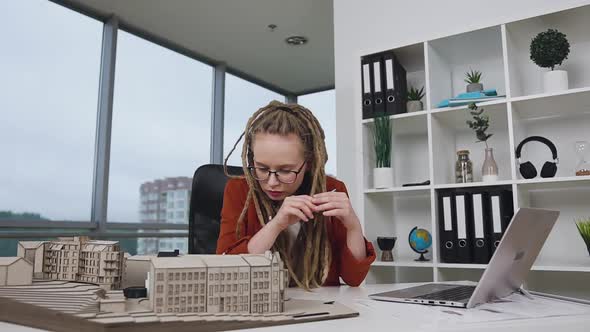 Female Architect with Dreadlocks Working with Wooden Model of New Buildings