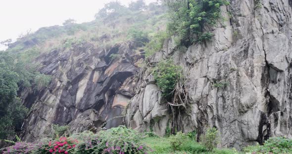 Dark Aged Shabby Cliff Face And Divided By Huge Cracks And Layers. Coarse, Rough Gray Stone Or Rock