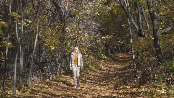 Young woman walking in yellow autumn forest