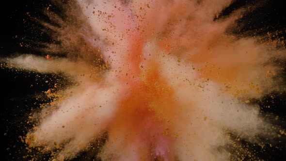 Colorful powder/particles fly after being exploded against black background. Slow Motion.