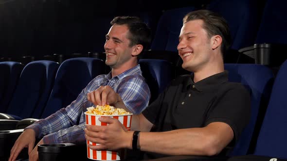 Two Male Friends Laughing While Watching Comedies at the Cinema