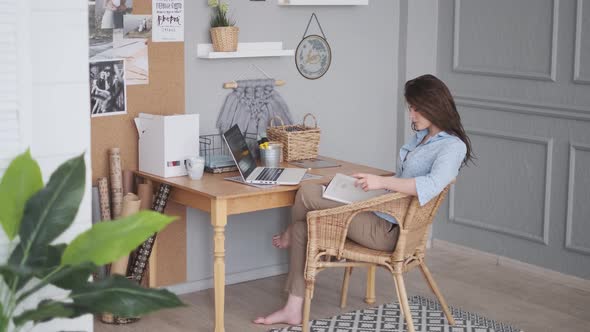 Young Woman Freelancer Reads Magazine in Home Studio