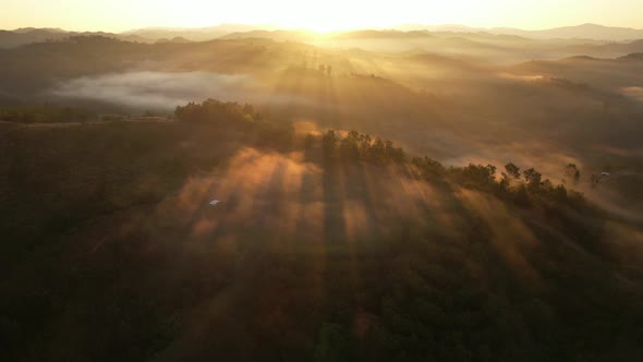 Aerial view of sunrise with fog above mountains. Golden hour and amazing sun rays. Nan, Thailand