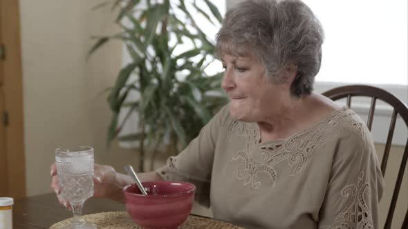 Elderly woman eating soup.