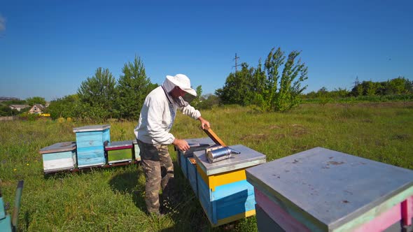 Beekeeper inspects bees. Apiarist on a bee farm on industrial pipes background.