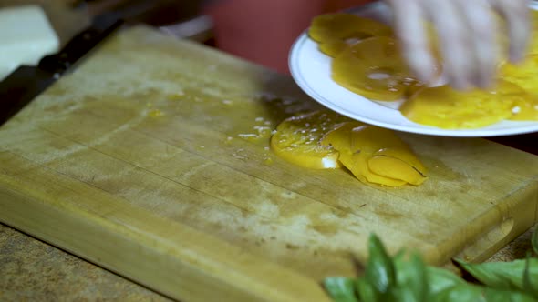 A cook arranges yellow heirloom tomato slices onto a white china plate.