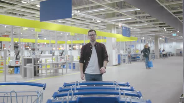 Handsome Guy Picking Trolley and Going Shopping in Store