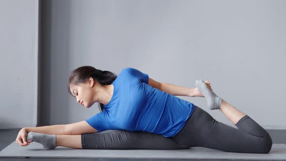 Full Shot Gymnastic Asian Young Woman Making Stretching on Mat at Home or Yoga Studio