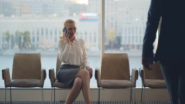 Businesswoman Sitting in Office Corridor Speaking on Cellphone