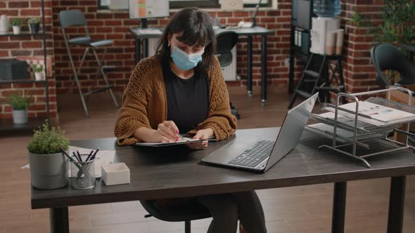 Woman Comparing Charts Information From Clipboard and Laptop