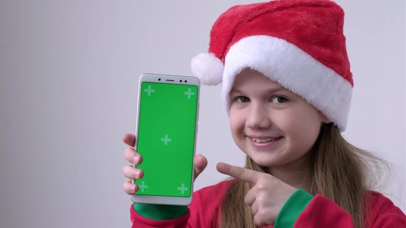 Little Girl in Christmas Santa Hat Shows Phone with Green Screen
