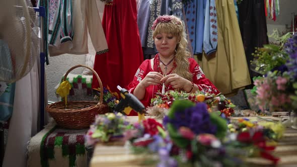 Portrait of Positive Woman Using Glue Gun Making Traditional Ukrainian Accessory in Craft Shop