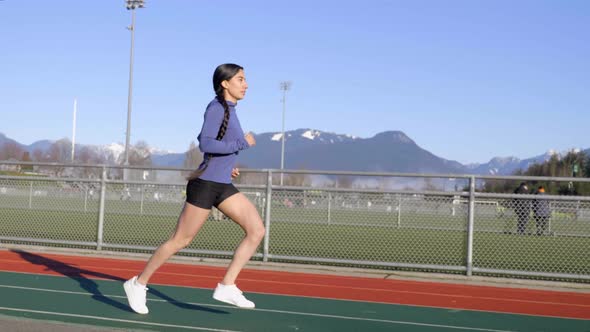 Athletic Latina Woman Jogging on Outdoor Track, Wide Follow Shot