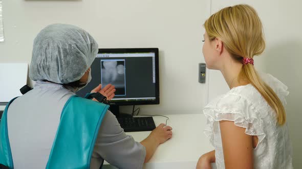 Dentist Discusses with Female Patient Plan for Recovery and Rehabilitation Both Looking at Xray