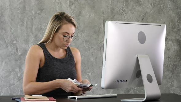 Young woman sit and counting money in the office