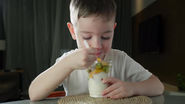 Child Eats Milk Yogurt with Tropical Fruits