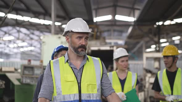 Male engineer foreman walking and explaining project to group of mechanic