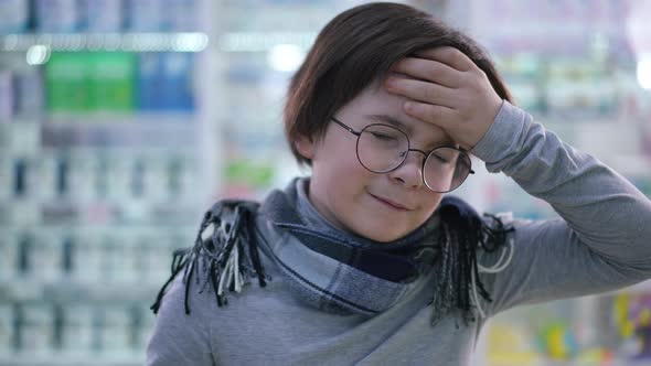 Closeup Caucasian Boy with Headache Posing in Pharmacy Indoors