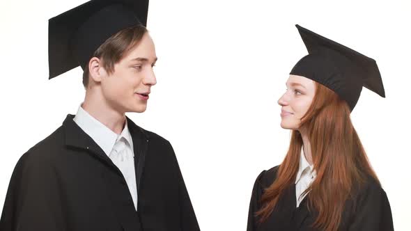 Young Caucasian Graduate Male and Female Standing on White Background in Lack Robes and Square