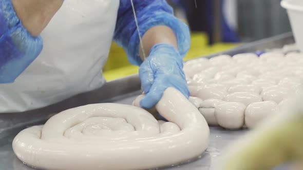 Sausage and Sausage Production Line. Workers in Manual Link Sausages