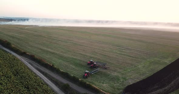 Tractors Plow the Field at Sunset