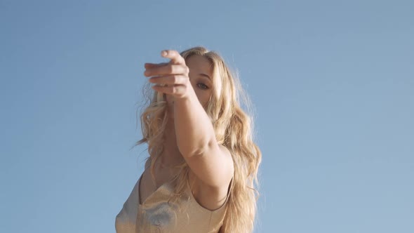 Woman Dancing In Gold Dress Under Blue Sky