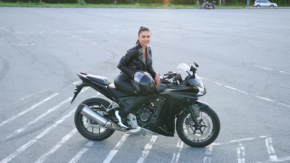 Female Biker in Leather Clothes which Posing on Luxurious Motorcycle