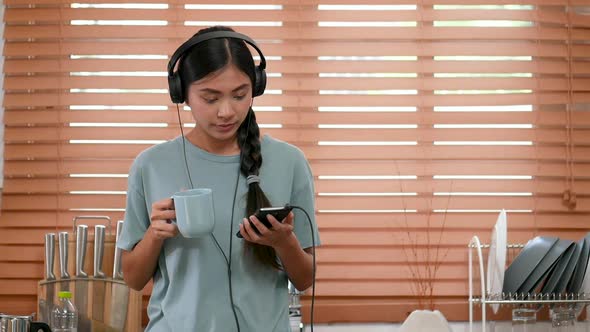 Young Asian woman using mobile phones at home and drinking coffee.