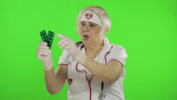 Elderly Female Doctor Talking To Camera. Tablet Blisters in Her Hand