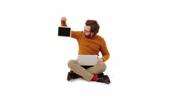 Bearded Caucasian Young Adult Man Holding Mockup Blackboard and Laptop on His Knees