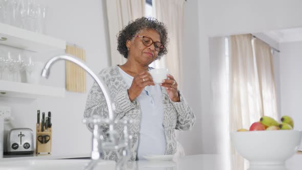 Senior mixed race woman enjoying drinking tea. Social distancing and self isolation in quarantine