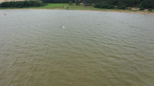 AERIAL: Rotating Shot of High Altitude of Kite Surfer in Green Baltic Sea