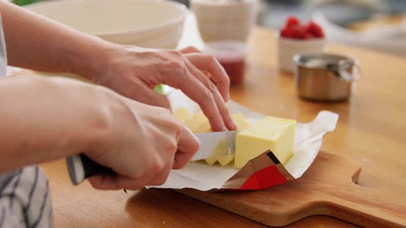 Hands Cutting Butter with Knife at Home Kitchen