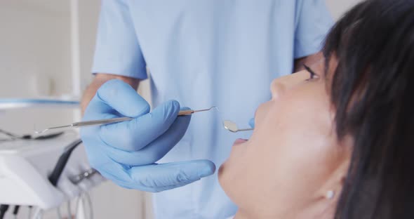 Caucasian male dentist examining teeth of female patient at modern dental clinic