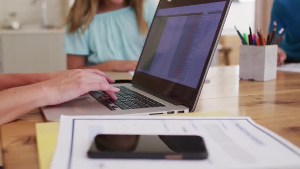 Mid section of woman using laptop while working from home